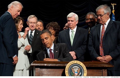 president barack obama signing an official document surrounded by vp joe biden, speaker nancy pelosi, and other members of congress